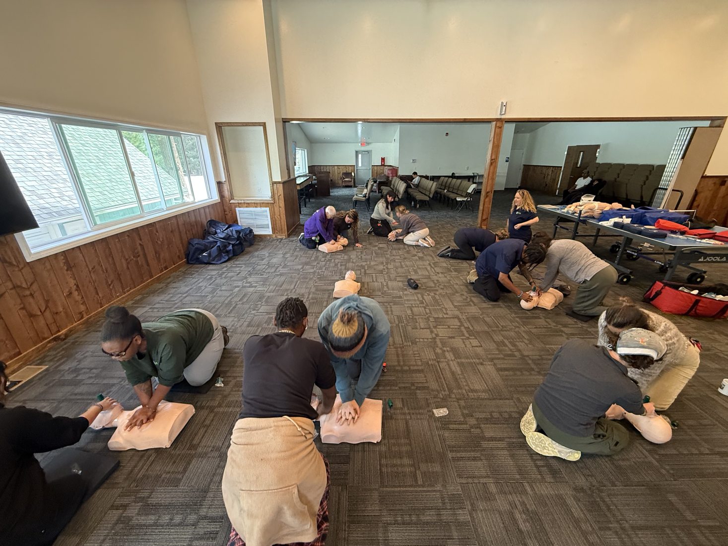 Group practicing CPR skills indoors with training manikins