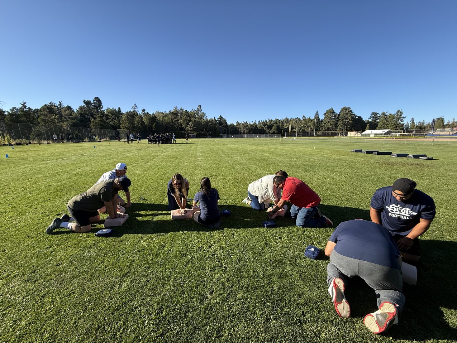Participants practicing CPR outdoors on a field